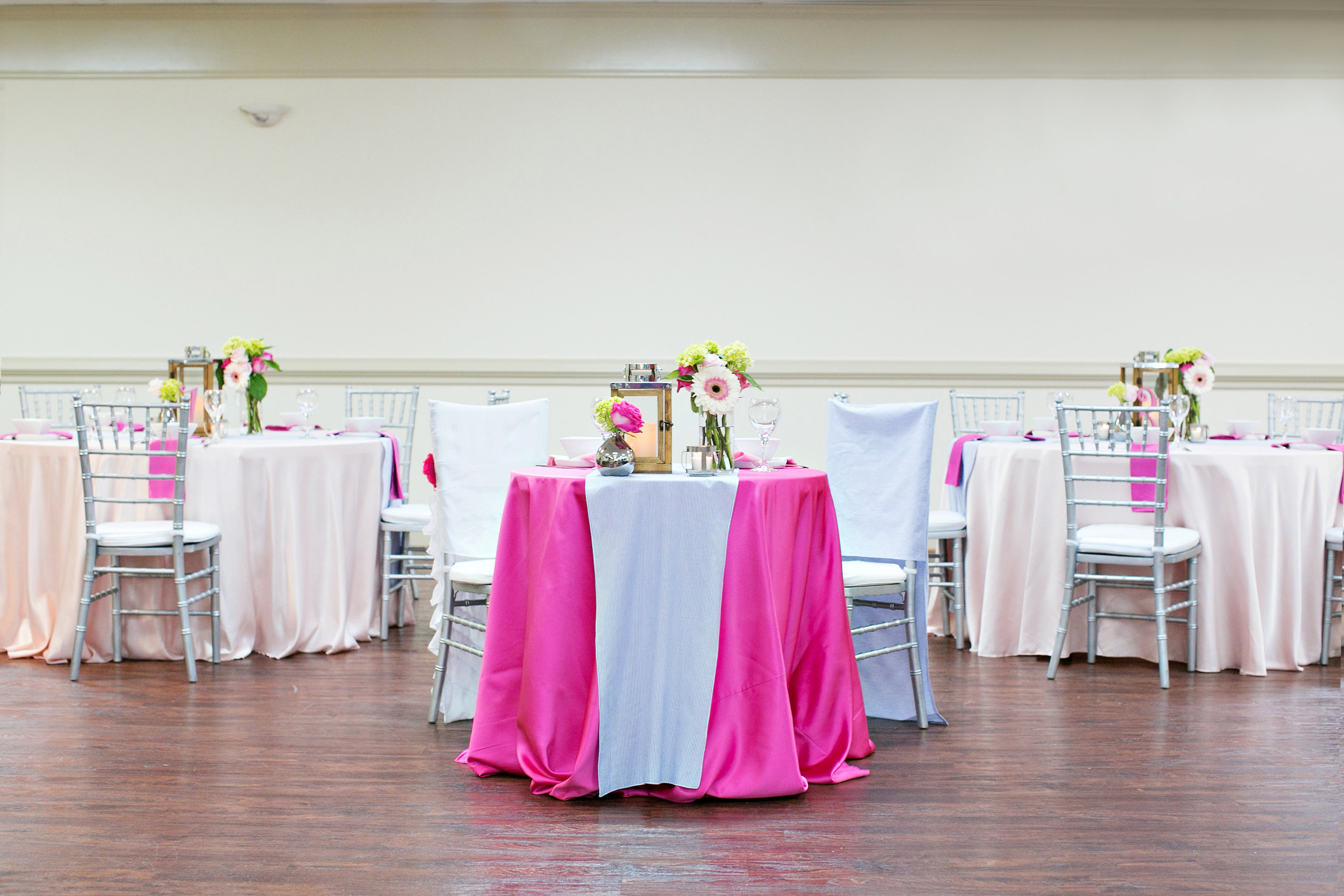 Hall decorated for a wedding reception with linens and centerpieces.